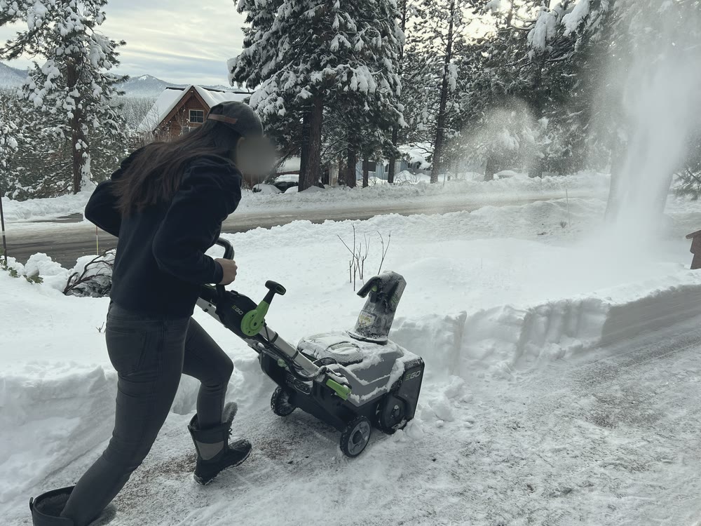 Mom pushing the snowblower, snow spraying